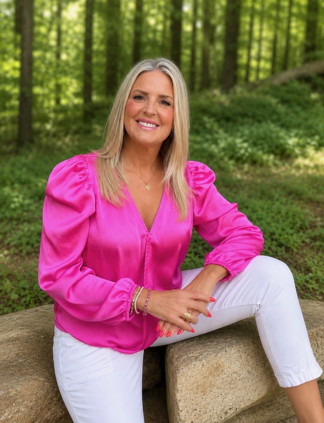Keely Smith, Realtor with Real Brokerage, LLC, in a pink blouse in a forest setting