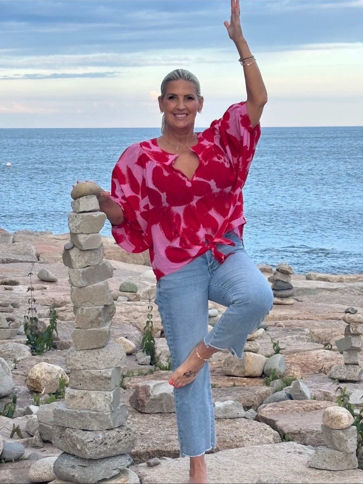 Keely Smith in tree pose on coastal rocks by the ocean